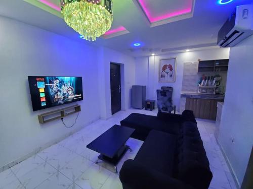a living room with a couch and a flat screen tv at Dinero Rose-2 Bedroom Apartment in Lagos