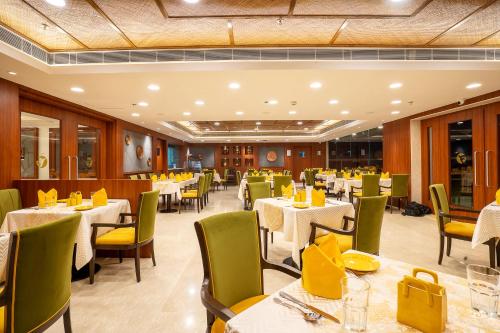 a restaurant with tables and chairs with yellow chairs at Fortune Park Pushpanjali, Durgapur - Member ITC Hotels' Group in Durgāpur