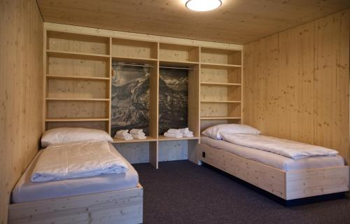 Duas camas num quarto com paredes e prateleiras de madeira em Frutt Living em Kerns