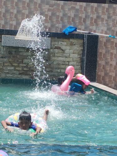 two children in a swimming pool with a fountain at Homestay Kemaman Private Pool Fyna in Kemaman