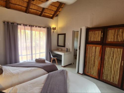 a bedroom with two beds and a desk with a window at Hoedspruit Bush Stay in Hoedspruit