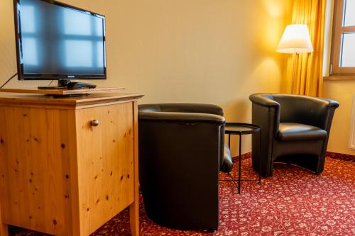 a hotel room with two chairs and a flat screen tv at Fichtelberghaus in Kurort Oberwiesenthal