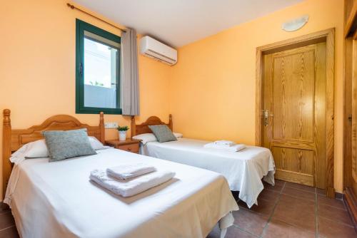 2 Betten in einem Zimmer mit orangefarbenen Wänden in der Unterkunft Apartamentos Punta Prima By EscapeHome in Punta Prima