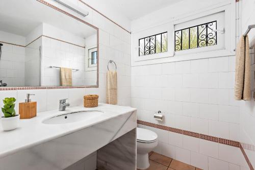 a white bathroom with a sink and a toilet at Villa Ribes in Binibeca