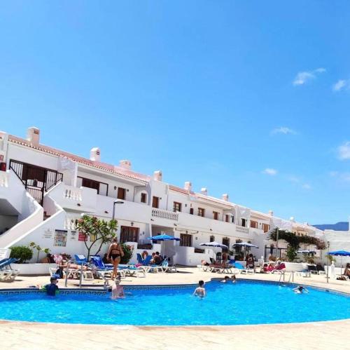 a hotel with a swimming pool in front of a building at 91 Port Royale Los Cristianos in Los Cristianos