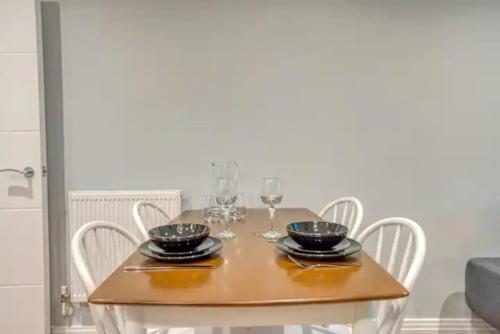 a wooden table with chairs and wine glasses on it at Luxury app in central Welwyn Garden, sleeps 4 in Welwyn Garden City