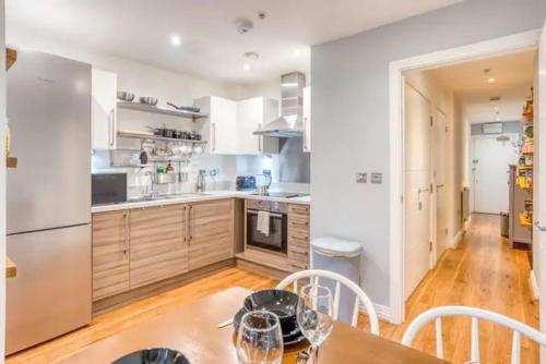 una cucina con tavolo in legno ed elettrodomestici bianchi di Luxury app in central Welwyn Garden, sleeps 4 a Welwyn Garden City