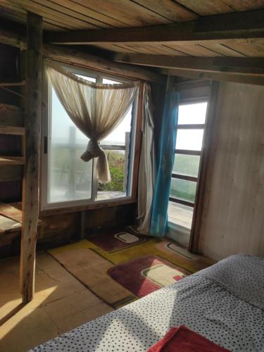 1 dormitorio con 1 cama y una ventana con cortinas en Mirando el Mar, en Barra de Valizas