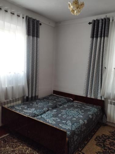 a bedroom with a bed in a room with windows at Guest house SONO adress Derbisheva 202 in Karakol