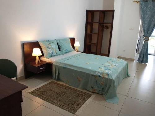um quarto com uma cama com um edredão azul em LES YILLAGA em Kribi