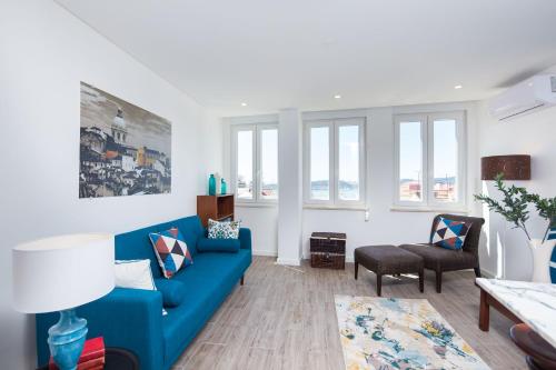 a living room with a blue couch and some windows at Designer Flats in Lapa by LovelyStay in Lisbon