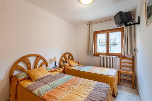 1 dormitorio con 2 camas y ventana en Apartamentos Vicenta en Valdelinares