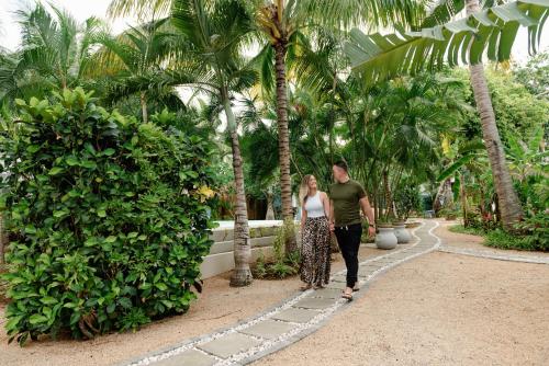 a man and woman walking down a path between palm trees at Bleu de Toi Boutique Guesthouse in Pereybere