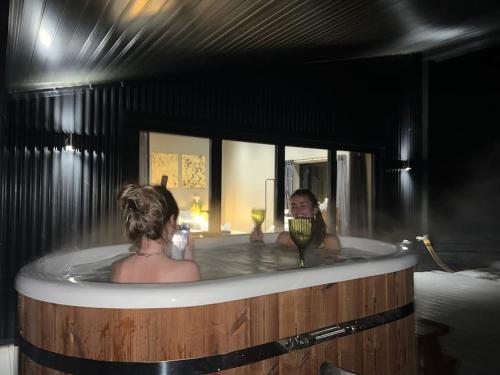 a woman in a bath tub with a woman holding a wine glass at Quirky, Luxury Hideaway in Llanbrynmair