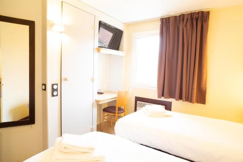 バイヨンヌにあるHôtel Les Genêts Bayonneのベッド2台と鏡が備わるホテルルームです。