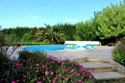 a swimming pool in a garden with pink flowers at Paradis des Outardes in Beauvoisin