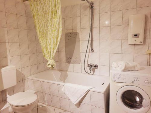 ein Badezimmer mit einer Badewanne, einem WC und einer Waschmaschine in der Unterkunft Appartementhaus Residenz Duenengarten in Kühlungsborn