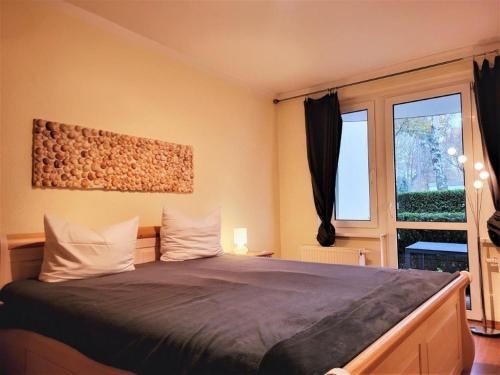 ein Schlafzimmer mit einem Bett und einem großen Fenster in der Unterkunft Appartementhaus Residenz Duenengarten in Kühlungsborn