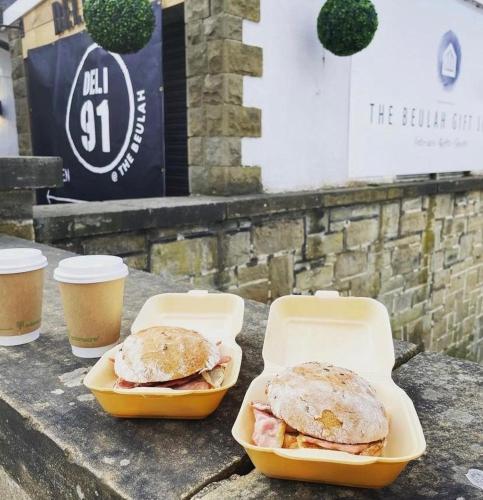 two sandwiches on a table with two cups of coffee at The Beulah Apartments in Leeds