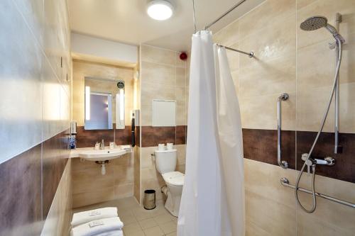 a bathroom with a shower and a toilet and a sink at B&B HOTEL Paris Nord Gonesse Parc des Expos in Gonesse