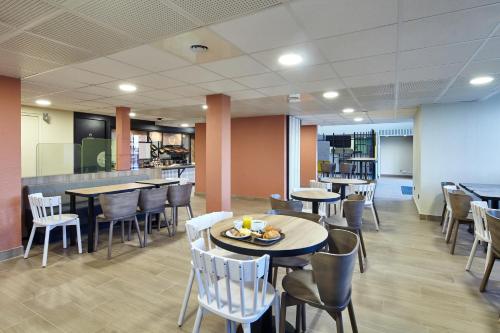 a restaurant with tables and chairs and a counter at B&B HOTEL Paris Nord Gonesse Parc des Expos in Gonesse