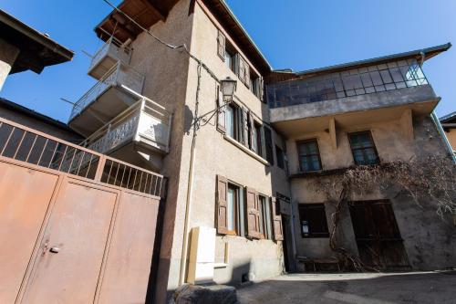 ein altes Gebäude mit einem Tor davor in der Unterkunft Le Coq Charmant petit studio en centre ville d'Embrun in Embrun