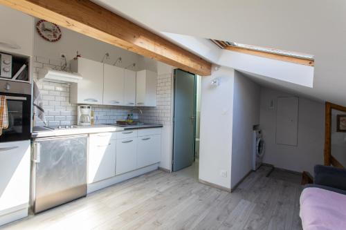 eine Küche mit weißen Schränken und einer blauen Tür in der Unterkunft Le Coq Charmant petit studio en centre ville d'Embrun in Embrun