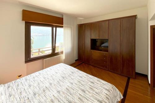 1 dormitorio con cama y ventana grande en Casa Pescarino con vista lago e idromassaggio, en Oliveto Lario