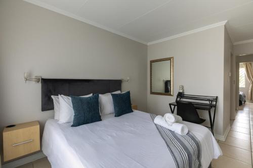 een slaapkamer met een groot wit bed met blauwe kussens bij Radstays - 43 Madison Palms in Johannesburg