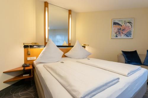 a bedroom with a large white bed with a mirror at Hotel am Stadtgarten in Radolfzell am Bodensee