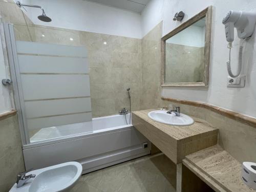 bagno con lavandino, vasca e specchio di Ambasada Suite a Roma