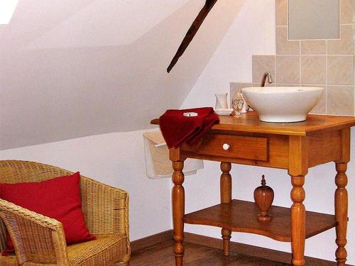 a bathroom with a sink and a table with a chair at Gîte Les 3 Voiles in Ploumilliau