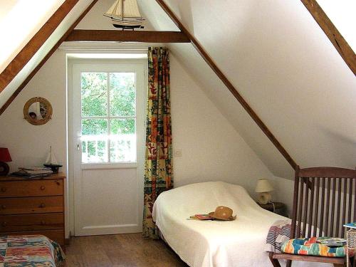 a attic room with a bed and a window at Gîte Les 3 Voiles in Ploumilliau