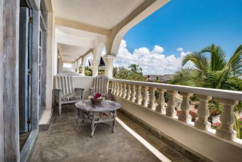 a balcony of a house with a table and chairs at Jacaranda Beach Resort in Watamu