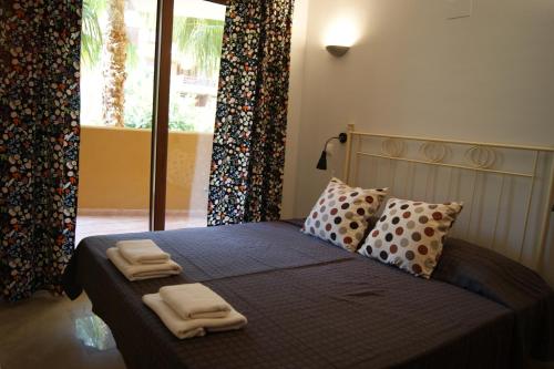 een slaapkamer met een bed met twee handdoeken erop bij Parque Recoleta 2 PISCINAS - CERCA DE PLAYA in Punta Prima