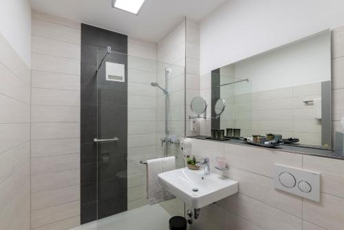 a white bathroom with a sink and a shower at Hotel am Stadtgarten in Radolfzell am Bodensee