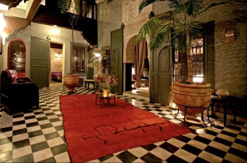 a living room with a red rug on a checkered floor at BKAN RIAD MARRAKECH in Marrakech