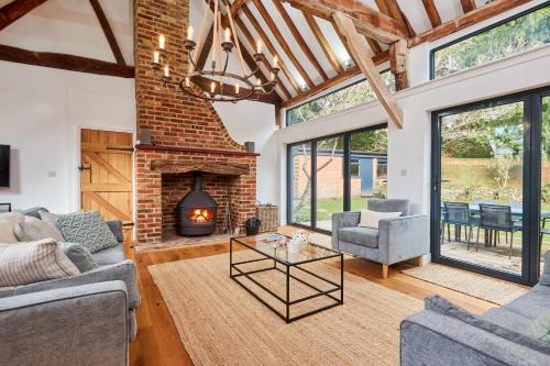 a living room with a brick fireplace and furniture at The Coach House, Hambledon in Hambledon