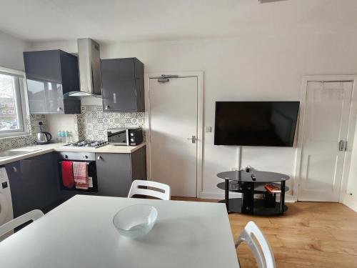 a kitchen with a white table and a kitchen with a tv at Grace Apartments - Living Stone 2 in Ashford