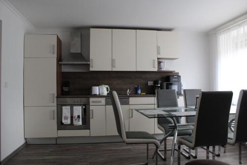 una cucina con armadi bianchi e tavolo con sedie di Eisenerzer Apartmenthaus a Eisenerz