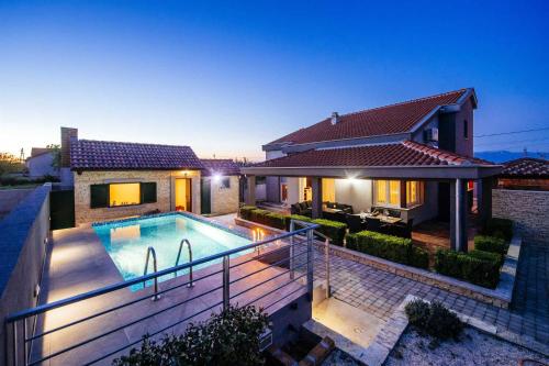 a house with a swimming pool in front of a house at Villa Enna with heated pool, Zadar in Crno