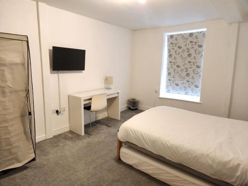a bedroom with a bed and a desk and a window at Grace Apartments - Living Stone 2 in Ashford