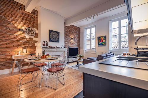Il dispose d'une cuisine et d'un salon avec un mur en briques. dans l'établissement Le Vélane 45m2 - Toulouse Centre - Proche Capitole, à Toulouse