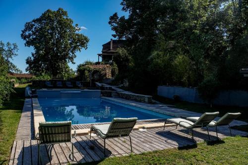 une piscine avec des chaises et une maison dans l'établissement Les Jardins de la Contie, à Lunan