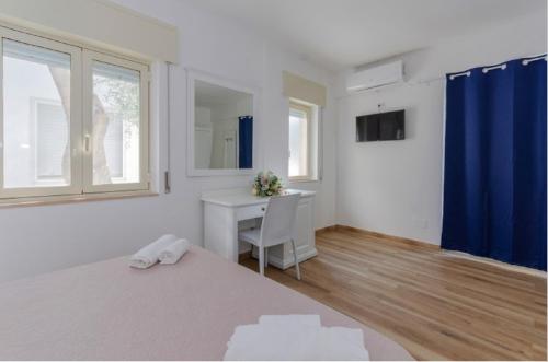 a bedroom with a desk and a bed with a blue curtain at Hotel Il Melograno in Mattinata