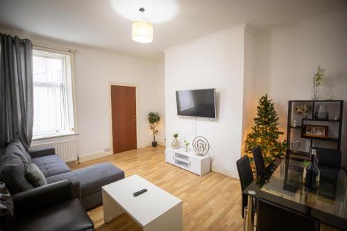 Sigmalife Apartment في نيوكاسل أبون تاين: غرفة معيشة مع أريكة وشجرة عيد الميلاد
