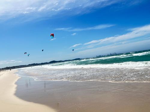 a group of people flying kites on the beach at Unique Kirra townhouse in Gold Coast