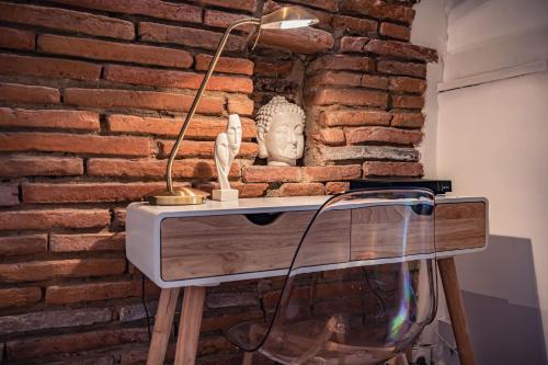 d'un bureau avec une lampe et un mur en briques. dans l'établissement Le Vélane 45m2 - Toulouse Centre - Proche Capitole, à Toulouse