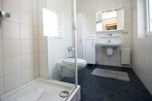 a white bathroom with a toilet and a sink at Yachthafenresidenz-Wohnung-9310-900 in Kühlungsborn