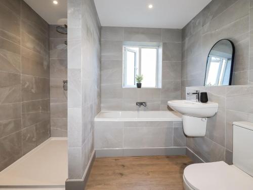 a bathroom with a tub and a sink and a toilet at Bimbling Cottage in Redruth
